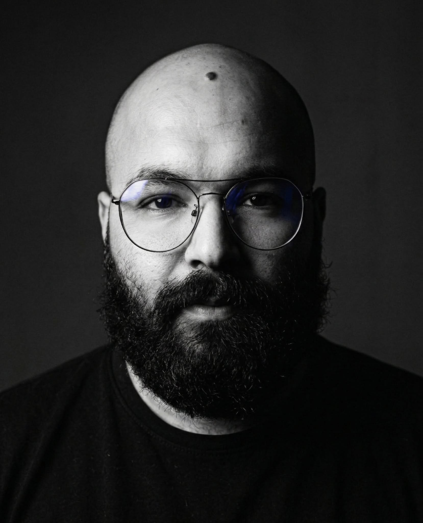 Black and white portrait of Mahmoud Ateyya wearing glasses